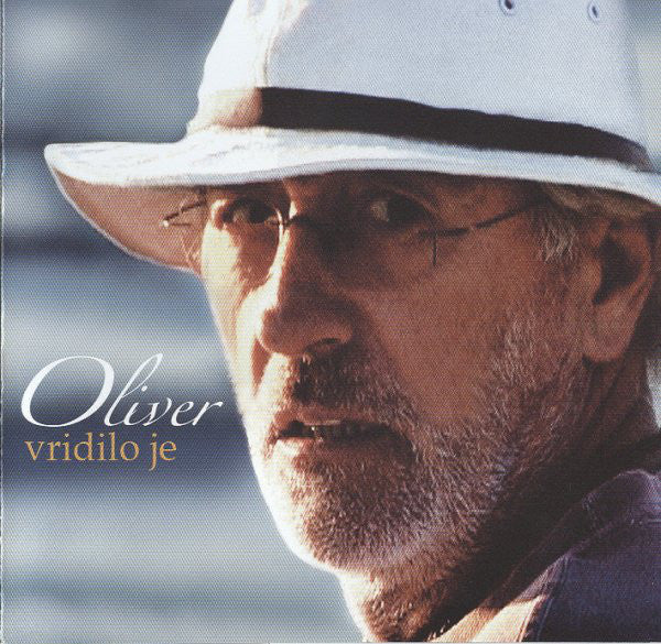 Album cover with a close-up of a person wearing a white hat and glasses, with text 'Oliver vridilo je' on a blurred background.