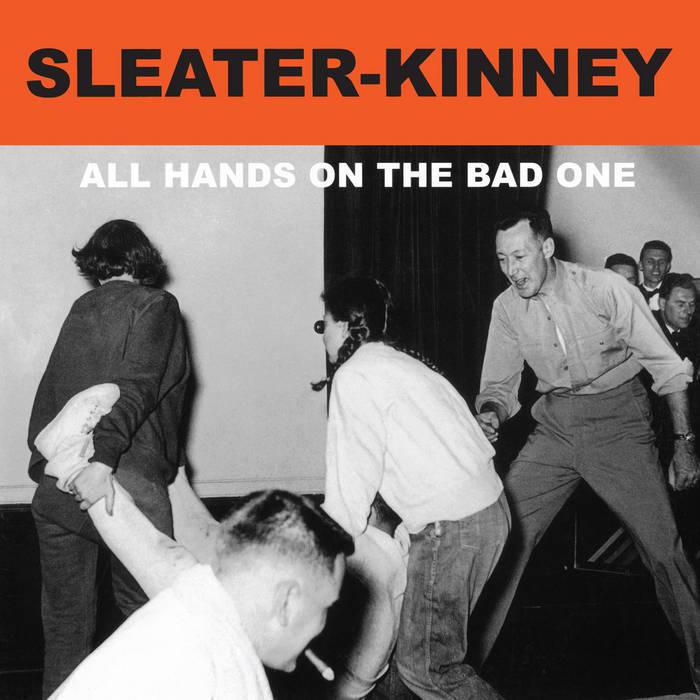 Album cover for 'All Hands on the Bad One' by Sleater-Kinney with black and white photo and text overlay two persons caring another for legs